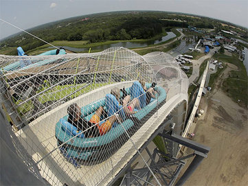 In this photo taken with the fisheye lens, riders go down the world´s tallest water slide called "Verruckt" at Schlitterbahn Waterpark, Wednesday, July 9, 2014, in Kansas City, Kan. The 168-foot-tall waterslide is scheduled to open to the public Thursday, after initially being slated to open May 23. (AP Photo/Charlie Riedel)